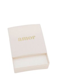 Scatola rettangolare bianca con una parte superiore curva. La parola "amor" è stampata in oro sul coperchio. L'interno è beige con una texture morbida.