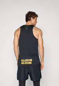 Schwarzes ärmelloses Tanktop mit abgerundetem Saum und Rückenschlitz. Auffälliger gelber Text am unteren Rand zeigt "42,195 KM 26,219 MI" an.