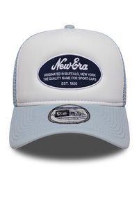 Hvid trucker cap med lys blå mesh bagside, prydet med et marineblåt oval badge med "New Era" tekst. Buet skygge, justerbar rem, tekstureret stof.