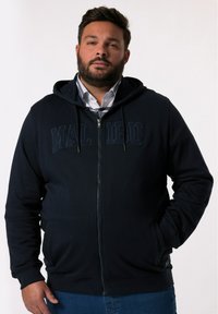 Marinblå zip-up huvtröja med en känguruficka, ribbade ärmavslut och fodrad huva. Har texten "MALIBU" i mörkare marinblått på bröstet.