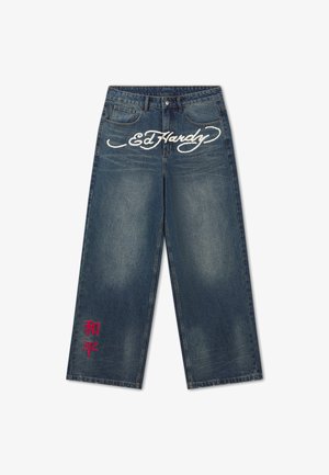 Jeans azules de pierna ancha con el logo blanco "Ed Hardy" en la parte frontal y caracteres asiáticos bordados en rojo cerca del dobladillo izquierdo.