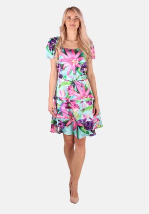 Das Blumenmusterkleid hat einen quadratischen Ausschnitt, Puffärmel und gestufte Rüschen. Die Farben umfassen Pink, Lila und Türkis in einem lebhaften Muster.