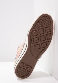 Bruine rubberen zool met een geometrisch loopvlakpatroon, bevestigd aan een stoffen bovenwerk in een multikleurenweving. Heeft een witte rand langs de rand.