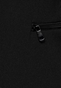 Czarna tkanina o płaskiej powierzchni z widoczną kieszenią na zamek. Zamek jest czarny z prostokątnym uchwytem, płynnie wkomponowanym.