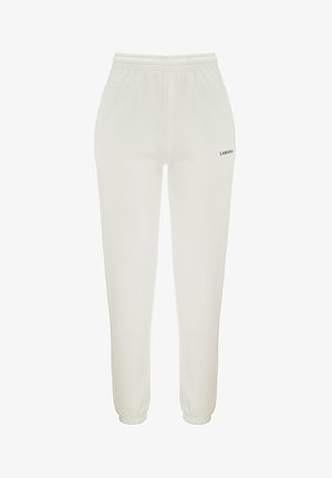 Pantaloni jogger albi cu talie elastică și manșete, având un mic logo text negru pe partea stângă. Textură de material neted.