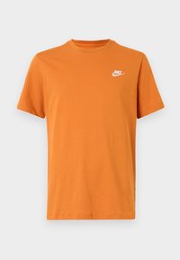Oranžové bavlněné tričko s kulatým výstřihem, krátkými rukávy a malým bílým logem Nike na levé straně hrudi. Hladká textura.