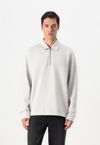 Light gray zip-up pullover with a collar, made from textured fabric, featuring long sleeves and a relaxed fit. Simple design with no patterns.
