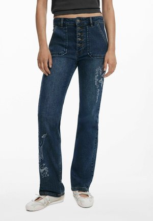Dark blue denim jeans with a high waist, featuring a button fly and embroidered designs of animals and stars on the left leg.
