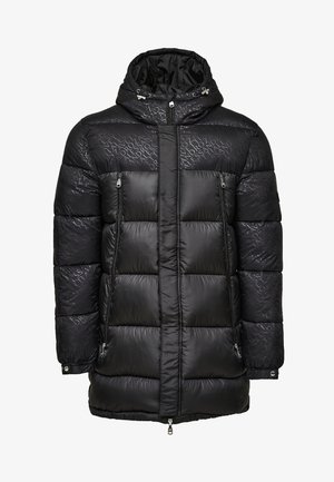 Veste en duvet noire avec capuche, présentant une texture matelassée, deux poches avant zippées et un marquage subtil dans un motif imprimé sombre.