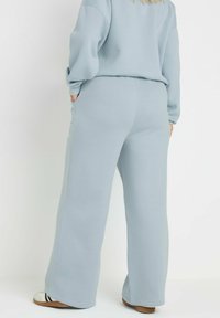 Ljust blå, högmidjade sweatpants med avslappnad passform, tillverkade av mjukt tyg. Sidofickor och en slät textur ökar komforten.
