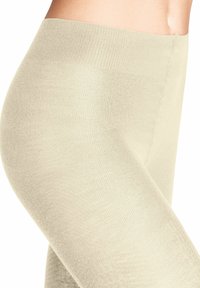 Leggings beige senza cuciture con fascia ribezzata, texture liscia e design aderente, che mostrano il lato e parte della fascia in vita.