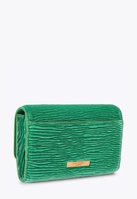 Pochette verte texturée en tissu avec une surface striée. Comprend une plaque logo en métal doré avec l'inscription « Kurt Geiger London ». Forme rectangulaire.