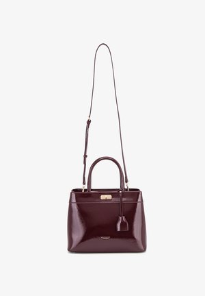 Bordeaux leren handtas met een glanzende afwerking, dubbele handvatten, een afneembare schouderriem, gouden hardware en een klein label dat aan de zijkant hangt.