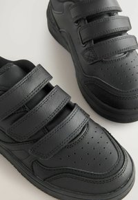 Sneaker in pelle nera con tre cinturini in velcro regolabili, design con punta perforata, pannelli laterali testurizzati e suola in gomma.