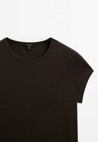 Maglietta marrone scuro con scollatura rotonda, maniche corte e una texture liscia e elastica. Le etichette sono visibili all'collo.