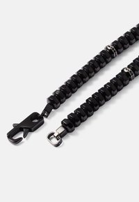 Cordão preto feito de contas hexagonais, com ganchos de metal em cada extremidade. Textura suave com um design uniforme.