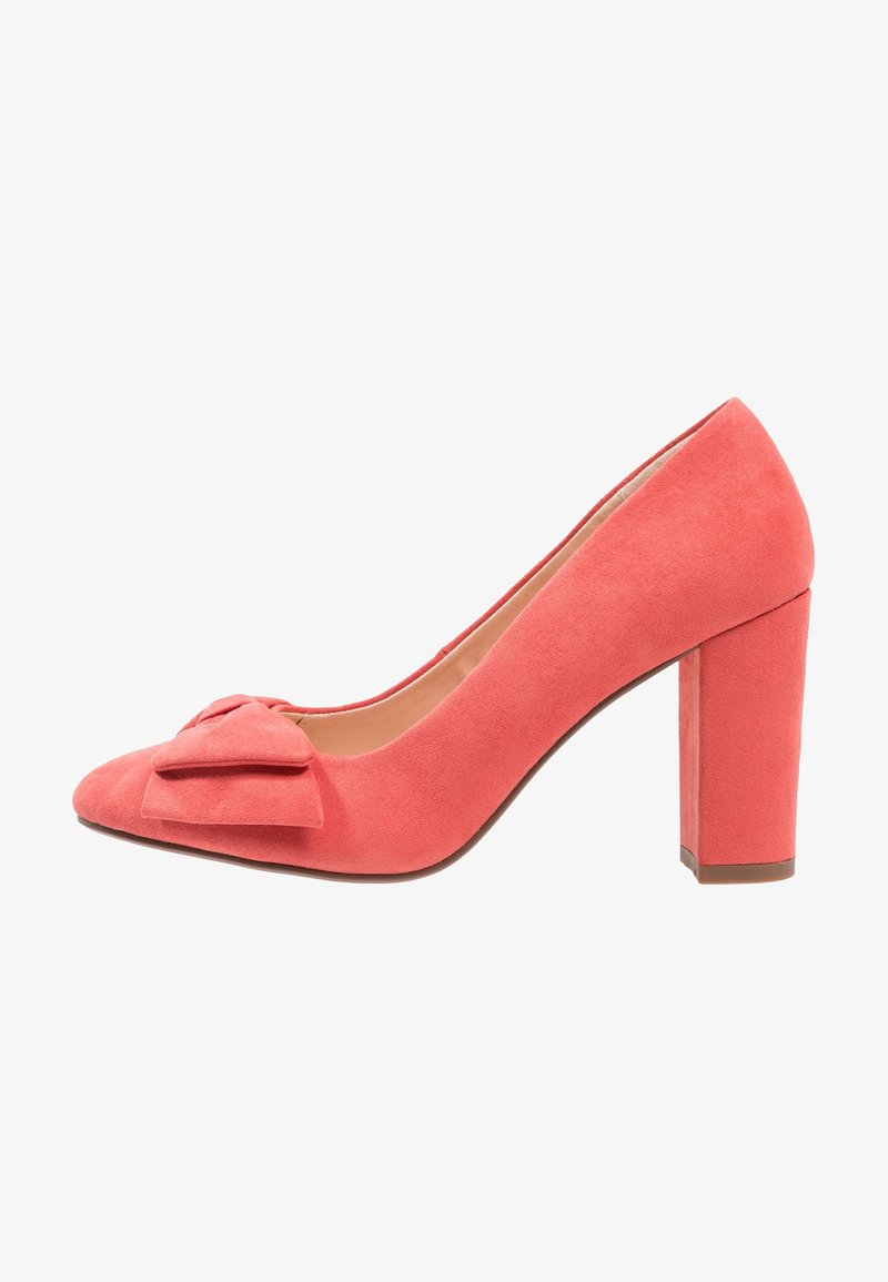Chaussure à talon haut en daim corail avec un talon bloc épais, un bout pointu et un nœud décoratif à l'avant, présentant une texture lisse.