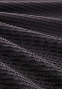 Tessuto nero testurizzato con un motivo a griglia, caratterizzato da quadrati in rilievo e una texture morbida e intrecciata. Molti pieghe drappeggiate creano profondità.