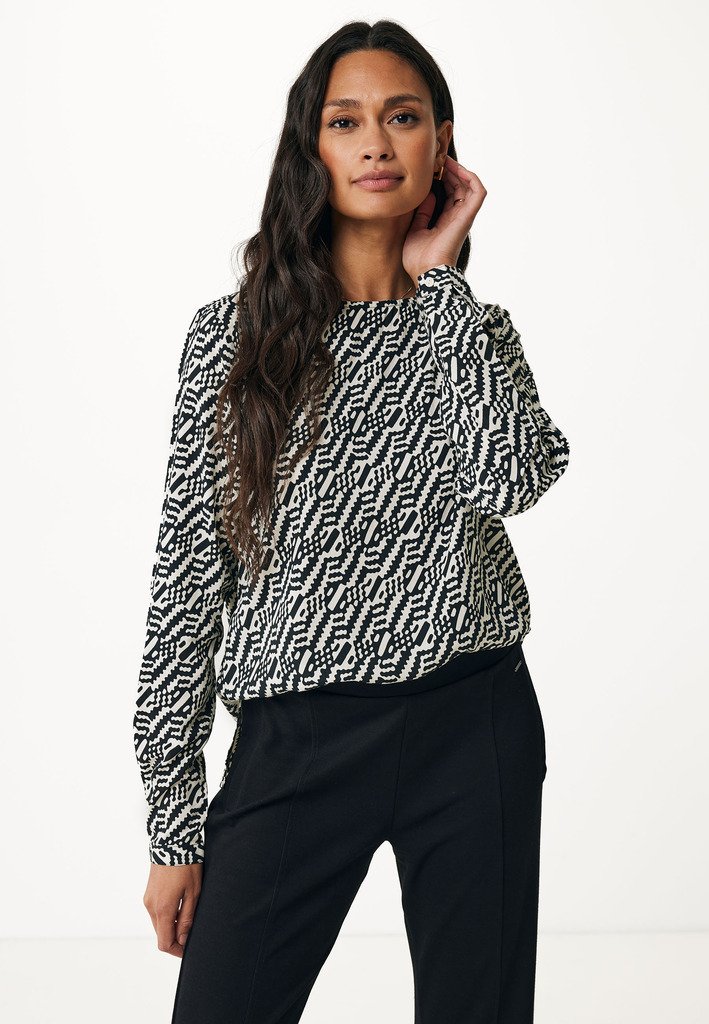 Maglietta a maniche lunghe bianco e nero con un fit morbido, caratterizzata da design geometrici e un collo rotondo, abbinata a pantaloni neri.