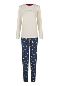 Kremowa bluzka z długim rękawem z napisem „North Pole Bakery”, w połączeniu z granatowymi spodniami ozdobionymi wzorami pierników, lasek cukrowych i choinek.