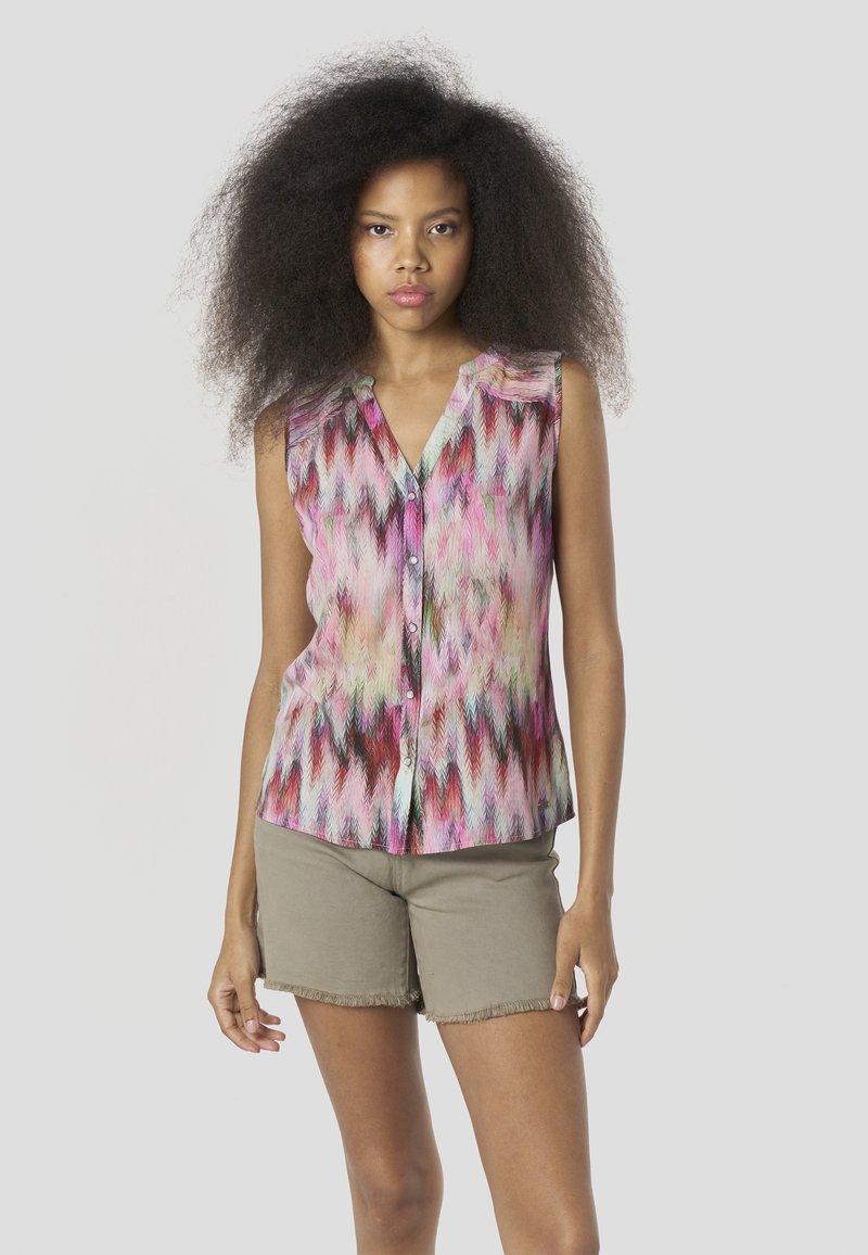 Blusa sin mangas colorida con un patrón de espina de pez en tonos rosa, rojo y verde. Presenta un escote en V y botones al frente.