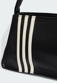 Mala de mão em couro preto com três linhas de costura branca paralelas, um design estruturado e uma textura suave.