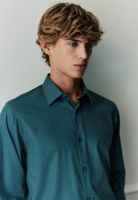 Teal button-up shirt featuring a subtle striped pattern, classic collar, and long sleeves, made from a smooth fabric with a slight sheen.