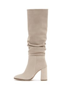 Bottes en suede beige, montant jusqu'au genou, avec un design décontracté, un bout pointu et un chunky talon haut. Texture lisse et accents sans couture.