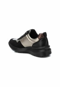 Zapatilla negra y dorada metalizada con una suela negra gruesa, materiales de ante y satén, diseño de cordones y una pequeña lengüeta en la parte trasera.