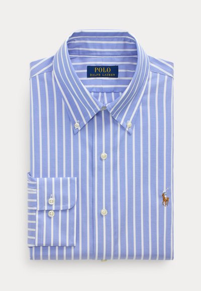 Camisa azul claro com riscas brancas verticais, colarinho abotoado e pequeno logótipo bordado de cavalo à frente. Tecido de algodão.