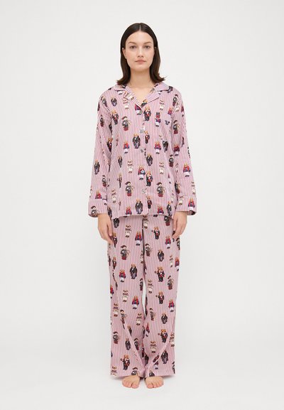 Baumwoll-Pyjama-Set mit einem pink-weißen Streifenmuster und Cartoonfiguren. Das Oberteil hat einen Knopfkragen; die Hose ist weit geschnitten.