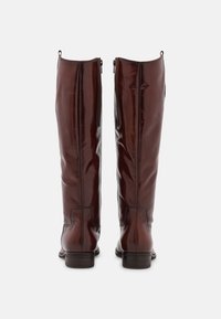 Bottes hautes en cuir brun foncé avec des talons empilés bas, des fermetures éclair latérales visibles et des languettes de tirage en haut, vues de dos.