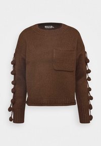 Pull en tricot marron avec un col rond, une poche avant et des pompons décoratifs le long des manches. Design court avec un ourlet côtelé.