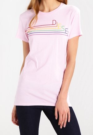 T-shirt rose clair à manches courtes avec le texte "DIESEL" multicolore formé par des lignes horizontales sur la poitrine, porté avec un pantalon foncé.