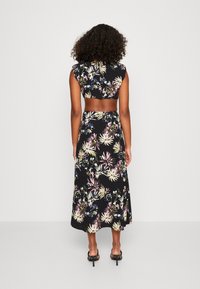 Blommig svart tvådelad outfit som har en kort topp med korta ärmar och en svängande, midi-lång kjol med ett livligt blommönster.