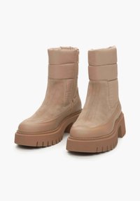 Beige enkellaarsjes met een gladde zijden afwerking, gevoerde schacht, robuuste bruine plateauzool en een rits aan de zijkant. Geweven details op de zool.