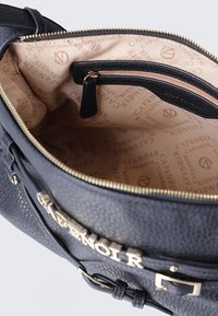 Borsa a mano in pelle nera con finitura testurizzata, hardware dorato e interno in tessuto con un motivo a logo ripetuto. Comparto con cerniera incluso.
