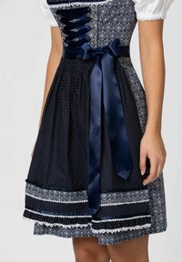 Dunkelblaues Kleid mit weißen Punkten, kontrastierendem gemustertem Rock, Satinband in der Taille und Spitzenverzierungen.