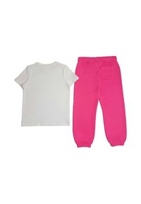 Maglietta bianca in cotone e pantaloni della tuta rosa con vita elastica e tasca laterale. I pantaloni hanno polsini a costine alle caviglie.