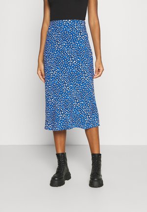 Blue midi skirt featuring an abstract pattern in white and black. Made of light fabric with a flowing design, paired with black combat boots.