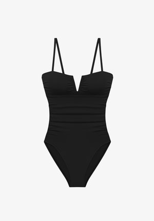 Costum de baie întreg negru, cu bretele subțiri și decolteu adânc în formă de V, pe fundal alb.