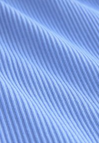 Textură de țesătură albastră cu nervuri verticale vizibile și pliuri moi care creează un model subtil de undă.