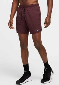 Bordeaux urheilushortsit vetoketjullisella vyötäröllä, sivutaskuilla ja heijastavalla Nike-logolla. Yhdistetty mustien lenkkareiden ja sukkien kanssa.