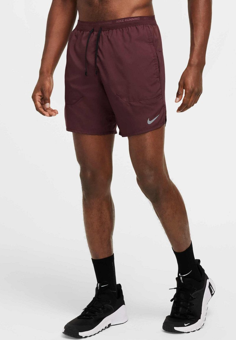 Bordeaux urheilushortsit vetoketjullisella vyötäröllä, sivutaskuilla ja heijastavalla Nike-logolla. Yhdistetty mustien lenkkareiden ja sukkien kanssa.