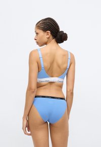 Ανοιχτό μπλε βαμβακερό σουτιέν και αντίστοιχο εσώρουχο, με ρυθμιζόμενους ιμάντες και ελαστικές μέσες με λεπτομέρειες λογότυπου. Ομαλή υφή και απλός σχεδιασμός.