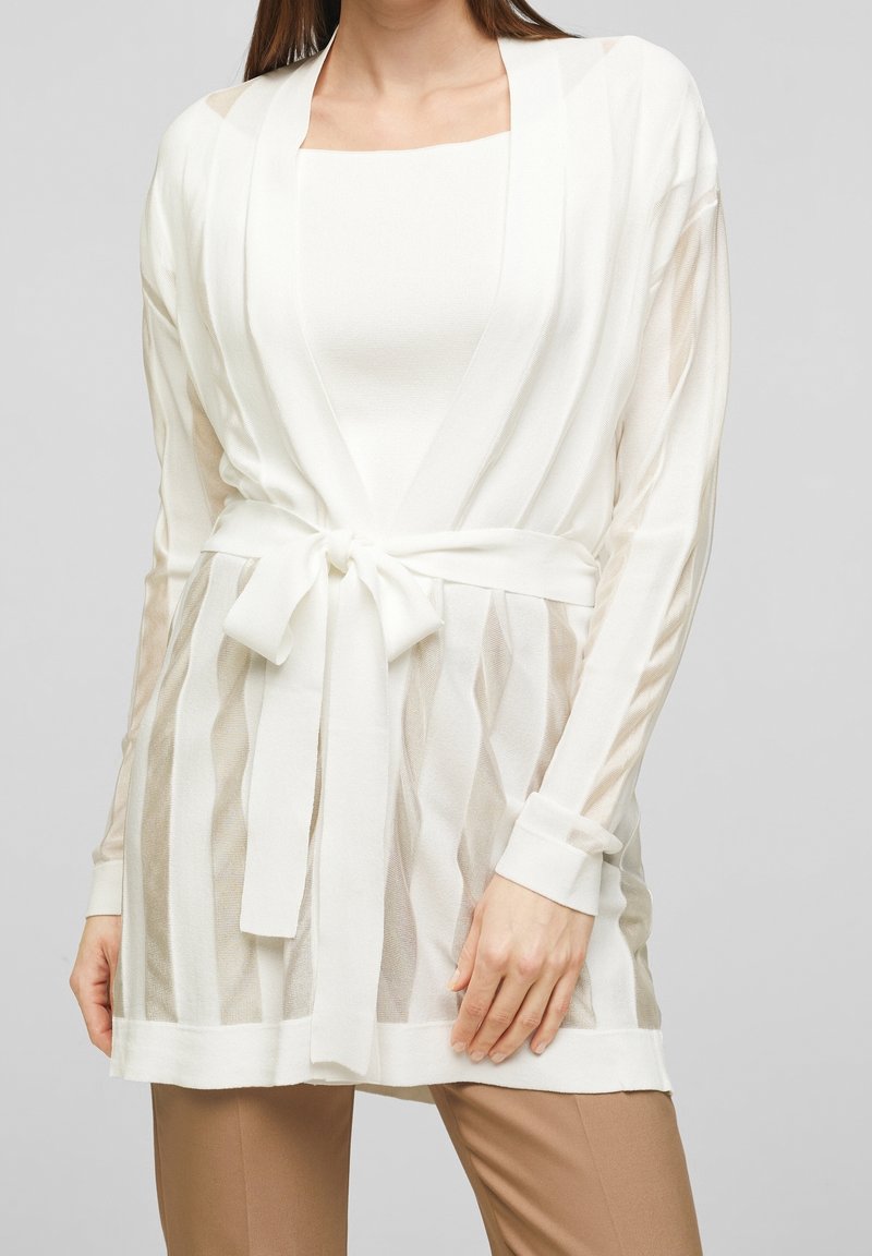 Biała, lekka kardigan z długimi rękawami, taliowany, z przezroczystym, paskowanym wzorem na gładkiej białej bluzce. Gładka faktura, luźny krój.