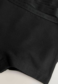 Boxeri scurți din bumbac negru, cu o textură netedă și un elastic în talie pe care se regăsește un logo subtil "NEXT". Design simplu, minimalist.