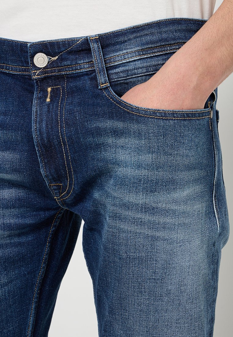 Dunkelblaue Jeans aus Denim mit geradem Schnitt, ausgestattet mit einer Vordertasche, sichtbaren Nähten und einem Knopfverschluss an der Taille.