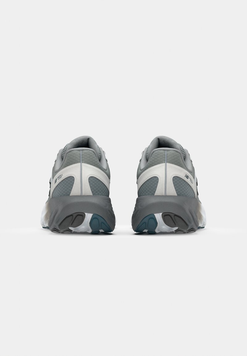 Grijze hardloopschoenen met een gestructureerde bovenkant, versterkte hiel en een gevoerde zool met een blauwe accent op de buitenzool.