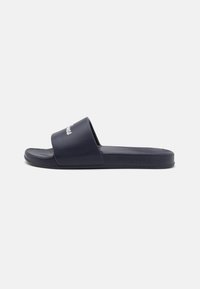 Sandales à glissière bleu marine avec une large sangle, fabriquées en matériau en caoutchouc lisse, dotées d'une semelle intérieure texturée et d'un détail de marque subtil.